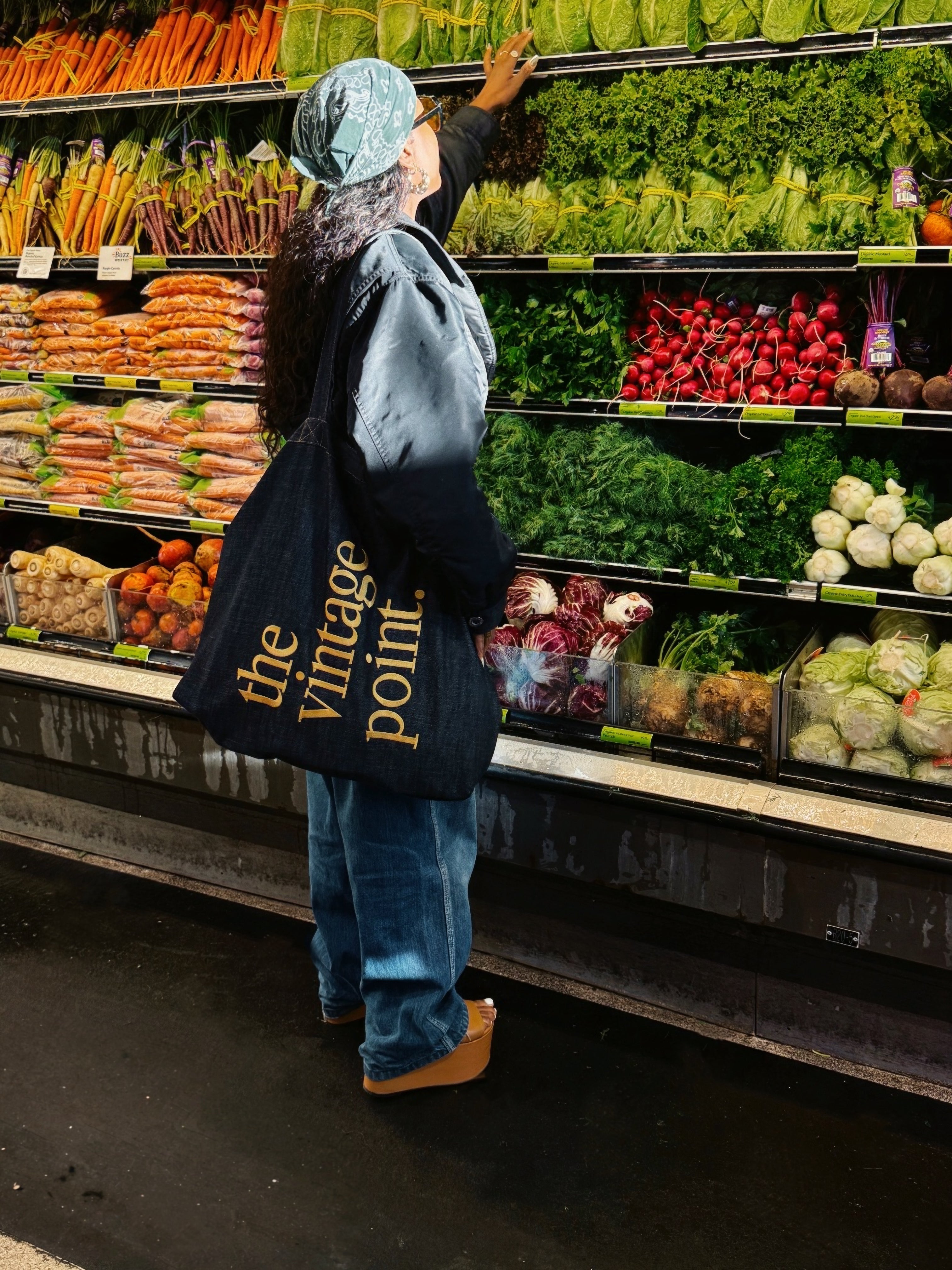 Person shopping in a grocery store with a 'the vintage point' bag.