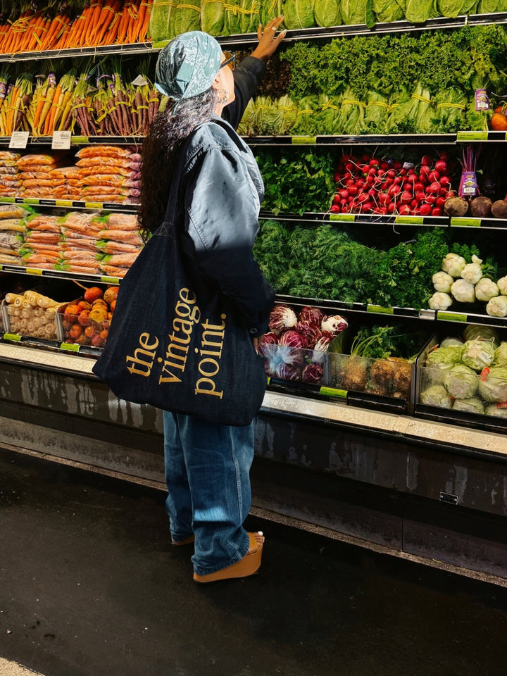 Person shopping in a grocery store with a 'the vintage point' bag.